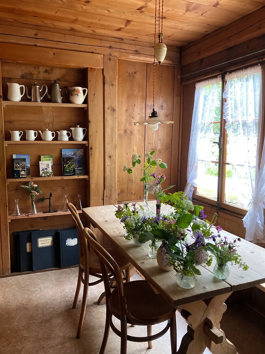 Tisch mit Wiesenblumen vor dem Geschirrregal