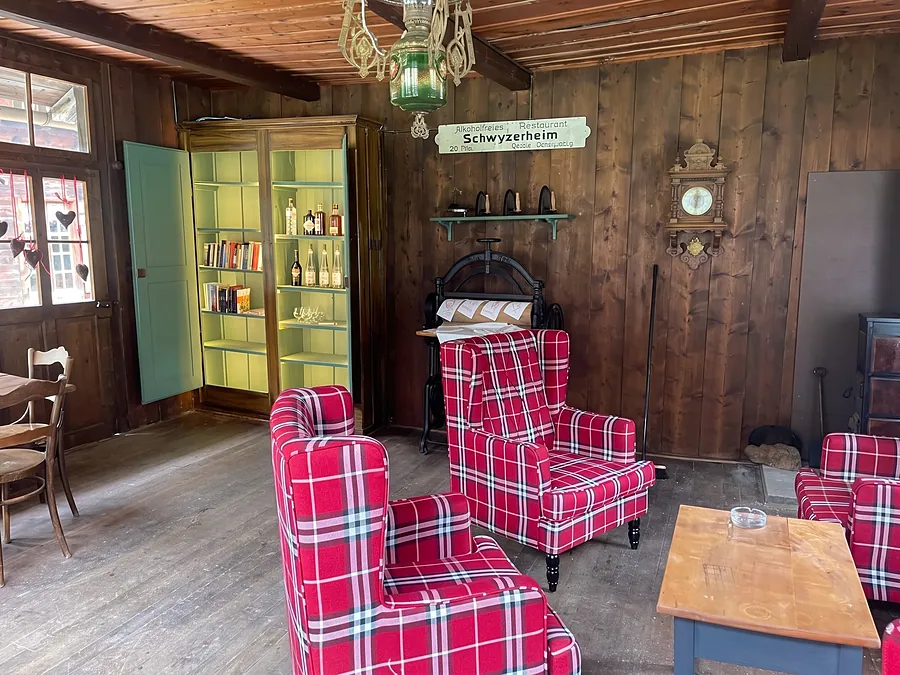 Stube mit rot karierten Sesseln und grünem Schrank